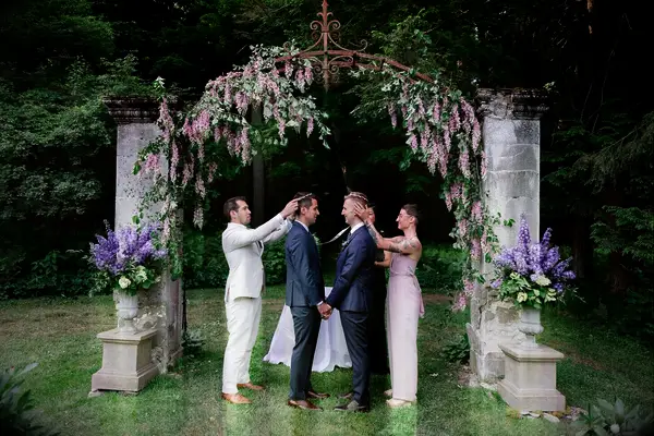 Greek stefana ceremony in front of wisteria-covered metal arch