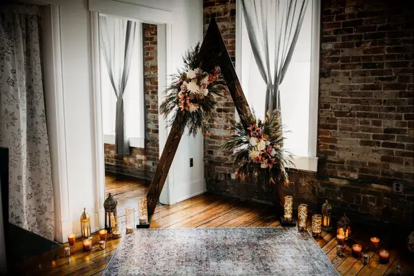 Wood triangle arch surrounded by candles in industrial venue with exposed brick