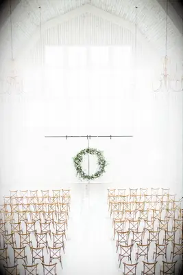 White barn with green circle arch and wood cross-back chairs