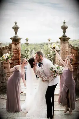Couple celebrating with wedding party during first kiss