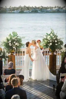 Couple leaning in and holding hands during wedding first kiss