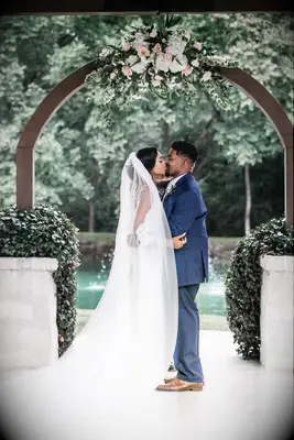 Couple kissing with hand behind head in front of arch