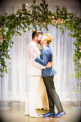 Couple in front of arch with romantic lean in kiss pose