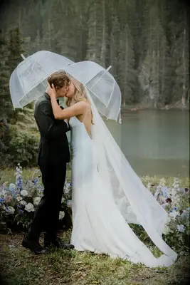 Couple kissing under umbrellas at wedding