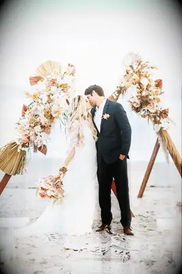 Couples first kiss on beach with wedding bouquet