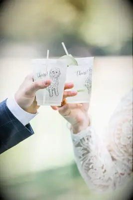Bride and groom toasting with virgin spritz mocktail in cutsom dog illustration cup