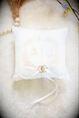 White linen ring bearer pillow with light pink monogram and laurel wreath