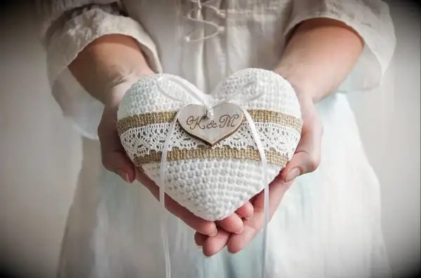White crochet heart shaped ring bearer pillow with couples initials