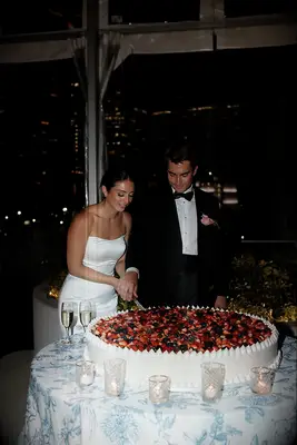 Couple cutting large fruit wedding cake