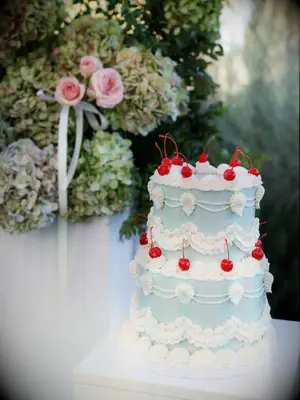 Blue wedding cake with white frosting and cherries