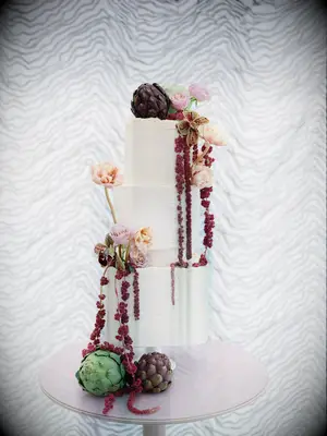 White tiered wedding cake with florals and veg