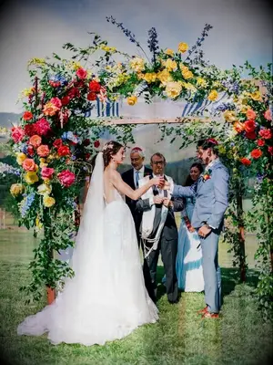 couple underneath colorful floral chuppah at Jewish wedding