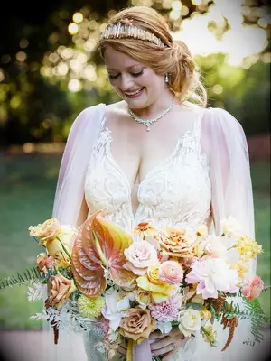 bride holding peach-hued anthurium and rose bouquet
