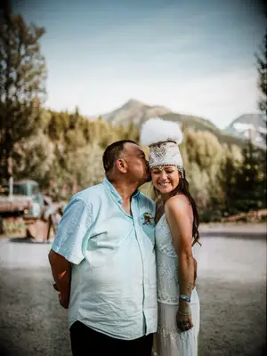 Father of the bride kissing Yupik Eskimo bride on the cheek