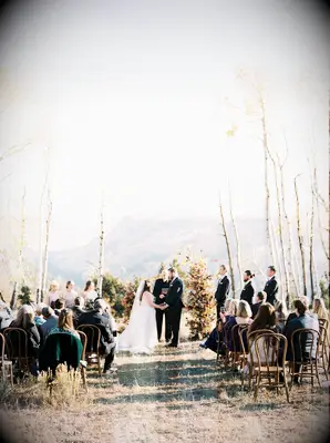 Bride and groom getting married at an outdoor rustic wedding ceremony.