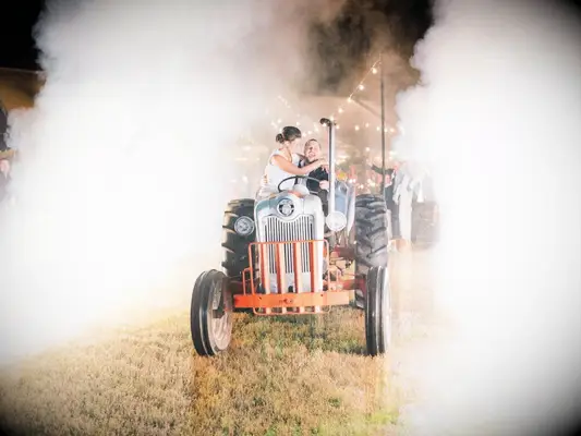 Bride and groom riding a tractor for their wedding exit.