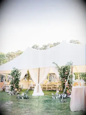 Outdoor tent at garden-themed wedding with gauzy white drapes