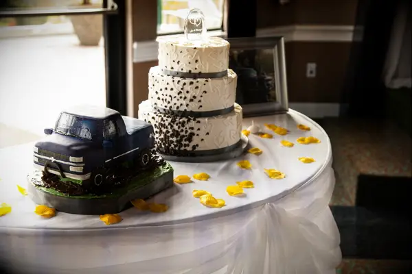 Pickup truck themed wedding cake pictured next to a classic white cake. 