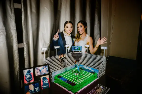 Couple poses in front of football-field shaped cake. 