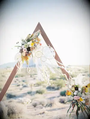 Triangular ceremony arch at boho wedding
