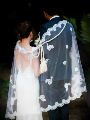 Bride and groom wearing veil and rope during traditional Lasso ceremony