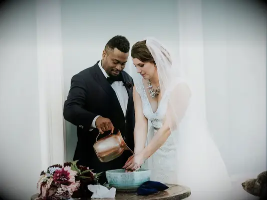 Bride and groom pouring water during hand-washing unity ceremony