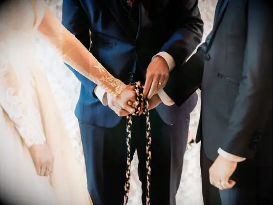 Bride and groom having hands tied with rope during traditional handfasting ceremony