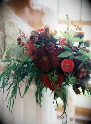 winter wedding bouquet with red dahlia, ranunculus, berries, roses and greenery
