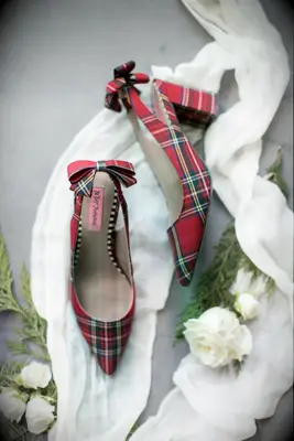 wedding flat lay with red tartan slingback high heels and white roses against gray backdrop