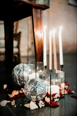 wedding decor with mini disco balls, white candles in square glass vases and red rose petals