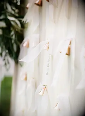 wedding escort card display with name tags written on ribbons tied to mini copper bells