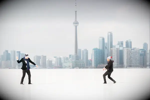 two groomsmen throwing snowballs with city skyline in the background