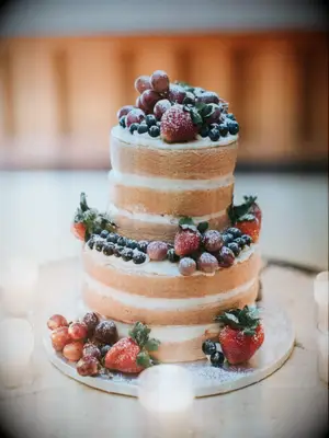naked wedding cake with powdered sugar and blueberries, strawberries and purple grapes