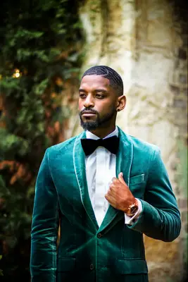 groom wearing emerald green velvet tuxedo with black bow tie