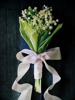 A petite lily of the valley bouquet tied with a white ribbon