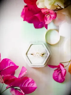A wedding engagement ring in ring box styled beside fresh bougainvillea flowers