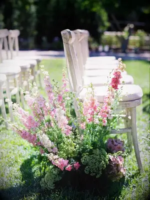 A pink delphinium flower arrangement as a wedding ceremony aisle decoration