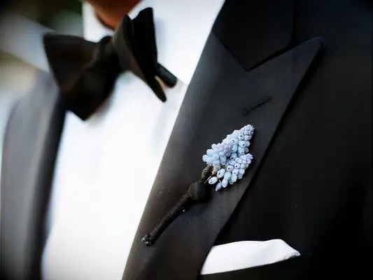 A blue muscari boutonniere on a black tux lapel