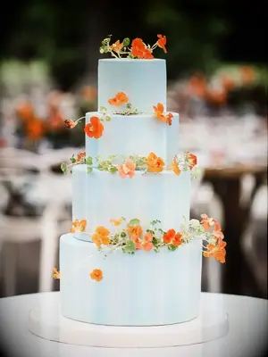Four-tier blue wedding cake decorated with orange nasturtium blooms