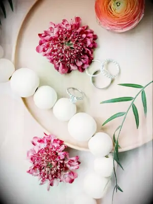 Flatlay with engagement rings and pink scabiosa blooms 