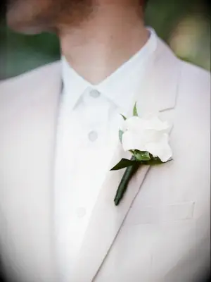 A gardenia boutonniere on the lapel of a neutral-toned suit