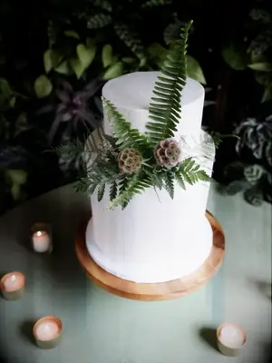Cake decorated with ferns and scabiosa pods