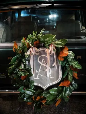 Magnolia leaf wreath with monogram sign on vintage getaway car