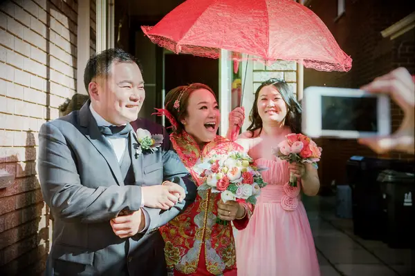 Bride walking under red fan during Chinese wedding