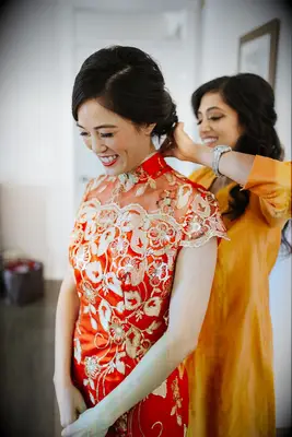 Bride getting dressed in qipao for Chinese wedding
