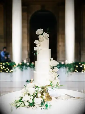 elegant white wedding cake decorated with white roses and greenery