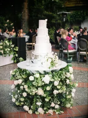 white wedding cake on greenery-covered cake table