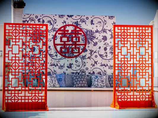 A red, white and blue double-happiness symbol (囍) over a relaxing seating area.