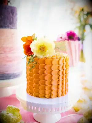 A summery orange buttercream wedding cake topped by fresh flowers.