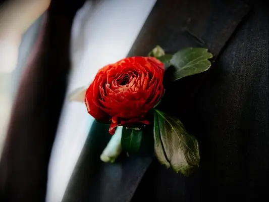 red ranunculus boutonniere on black suit lapel